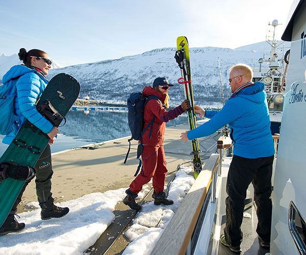 people carrying skies onboard a boat